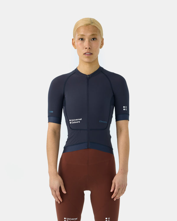 Model wearing the Women's Chroma Short Sleeve Jersey in Midnight Blue, paired with rust brown bib shorts, front view.