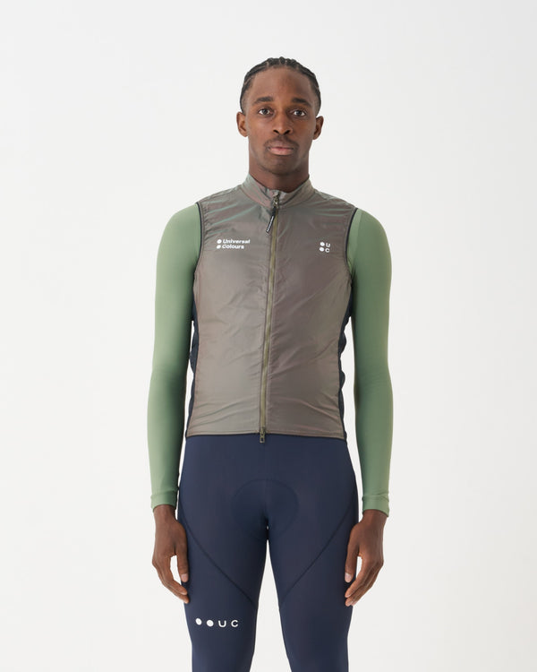 Male model in the Spectrum Gilet 2.0 in Iridescent Green/Red, front view, over a sage long-sleeve base layer and navy bibs.