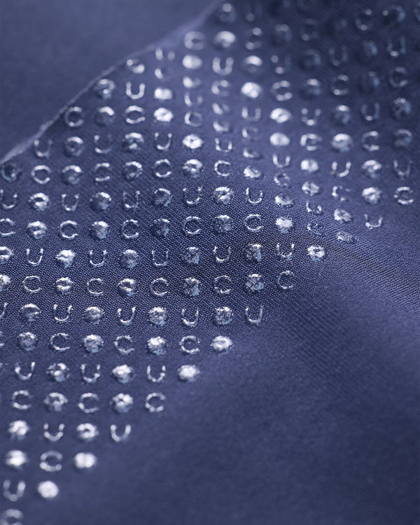 Macro of the silicone gripper on the Navy Blue Knee Warmers: repeated U and C dot motifs forming the UC monogram pattern.