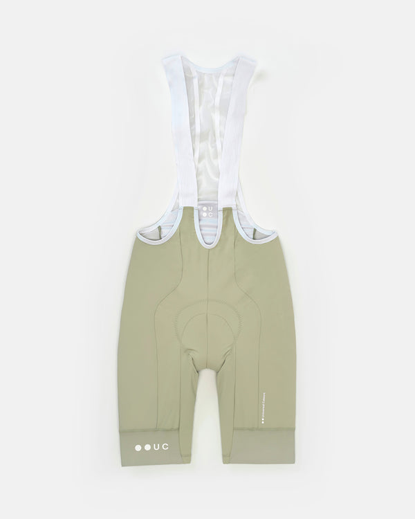 Flatlay of the Men's Mono Bib Shorts 2.0 in Green Tea with white mesh bib straps, contoured chamois and UC hem roundel.