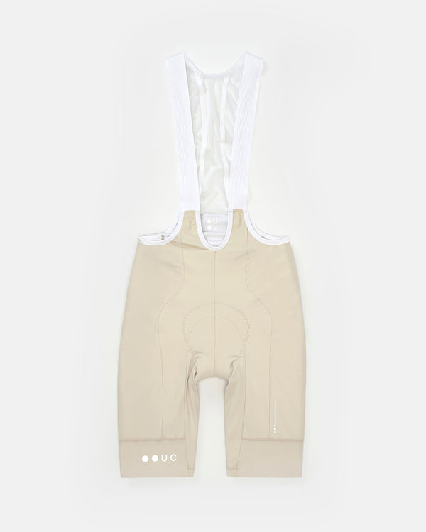 Flatlay of the Men's Mono Bib Shorts 2.0 in Off White with white bib straps, chamois and reflective UC hem roundel.