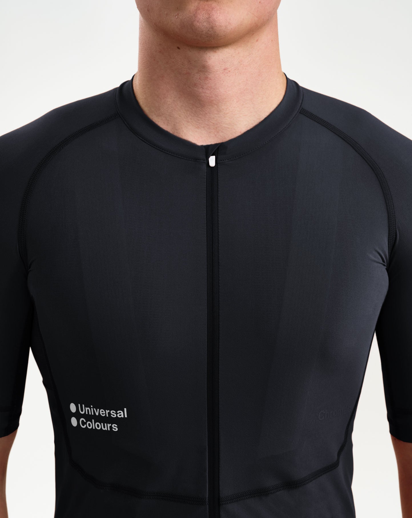 Close-up: low collar, full-length zip and Universal Colours chest wordmark on the Men's Chroma Jersey in Black.