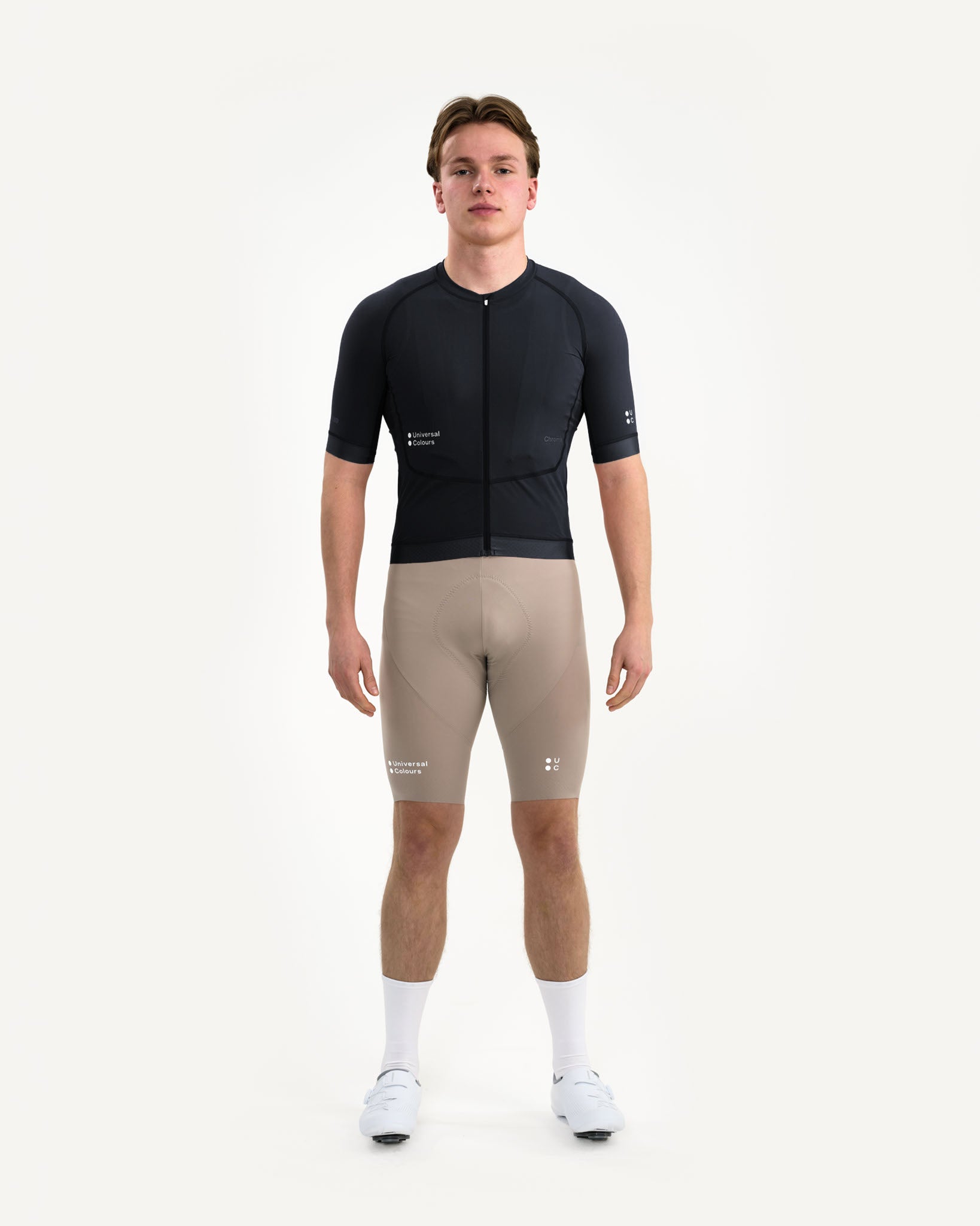 Front view: model in the Men's Chroma Short Sleeve Jersey in Black, paired with almond UC bib shorts and white shoes.