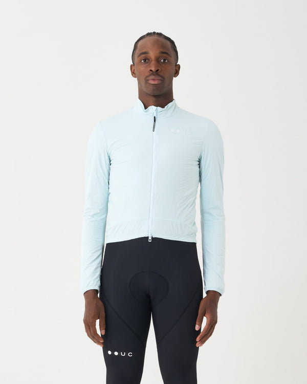 Model wearing the Men's Mono Insulated Jacket in Misty Blue, front view, paired with black UC cycling bib tights.