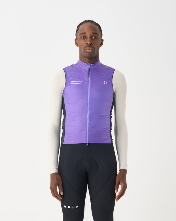 Male model in the Spectrum Gilet 2.0 in Amethyst Purple, layered over a cream base layer with black cycling bib tights.