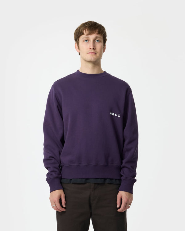 Model wearing the Unisex Sweatshirt in Hard Purple, front view, paired with deep brown chinos for a tonal contrast.