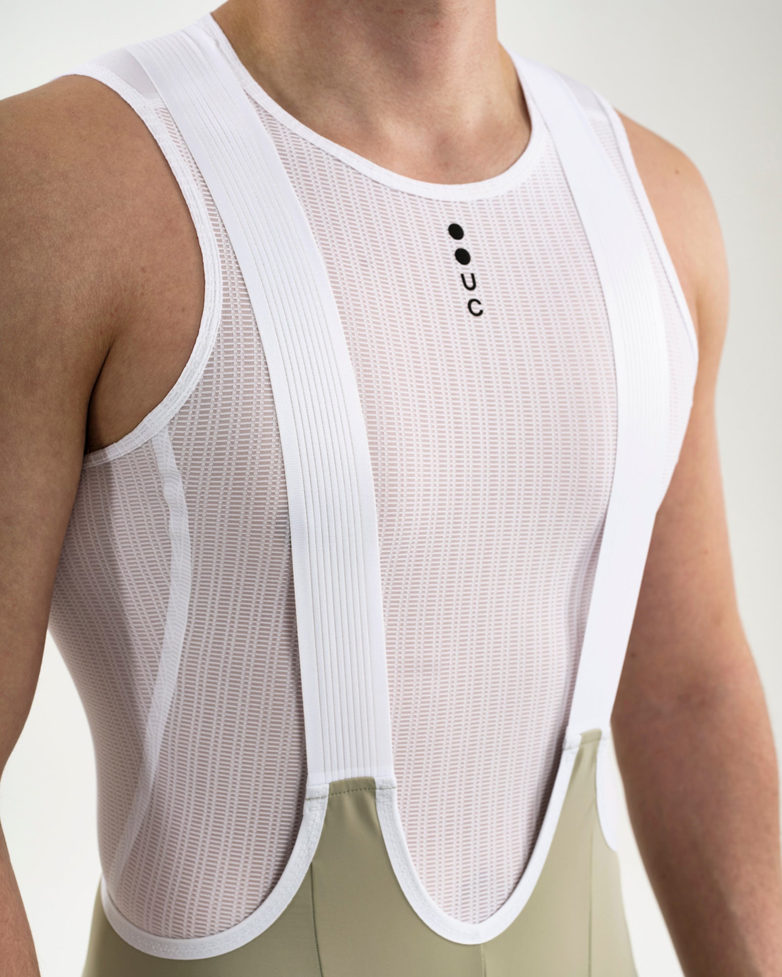 Close-up of the white UC mesh base layer worn under the Men's Mono Bib Shorts 2.0 in Green Tea, showing UC chest mark.