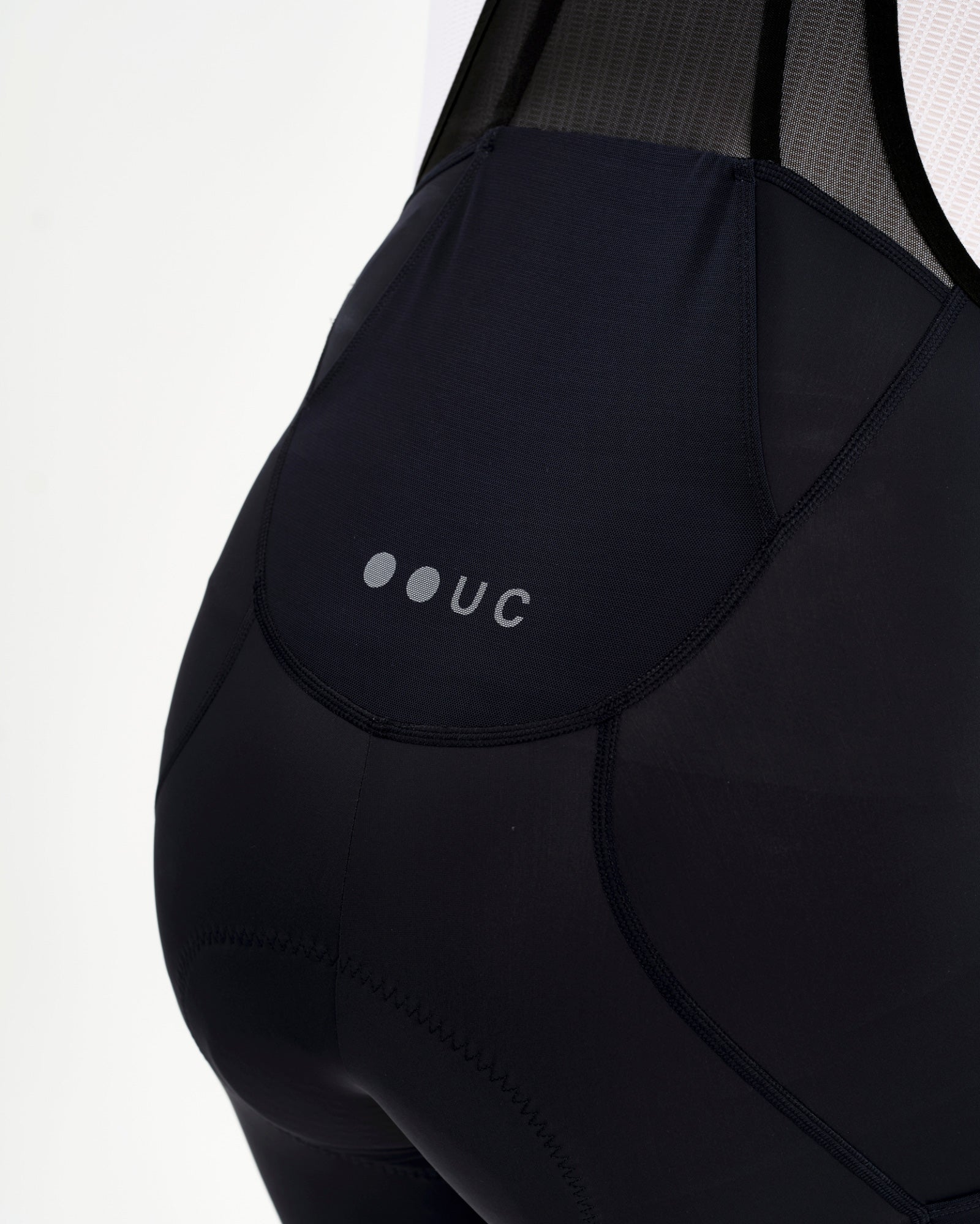 Rear cargo pocket detail: mesh-panelled central pocket and tonal UC dot-logo on the Men's Mono Cargo Bib Shorts in Navy Blue.