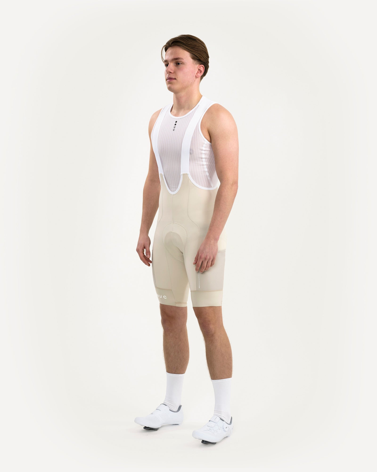 Three-quarter front view of the Men's Mono Cargo Bib Shorts in Off White on model, with white mesh base layer and bib straps.