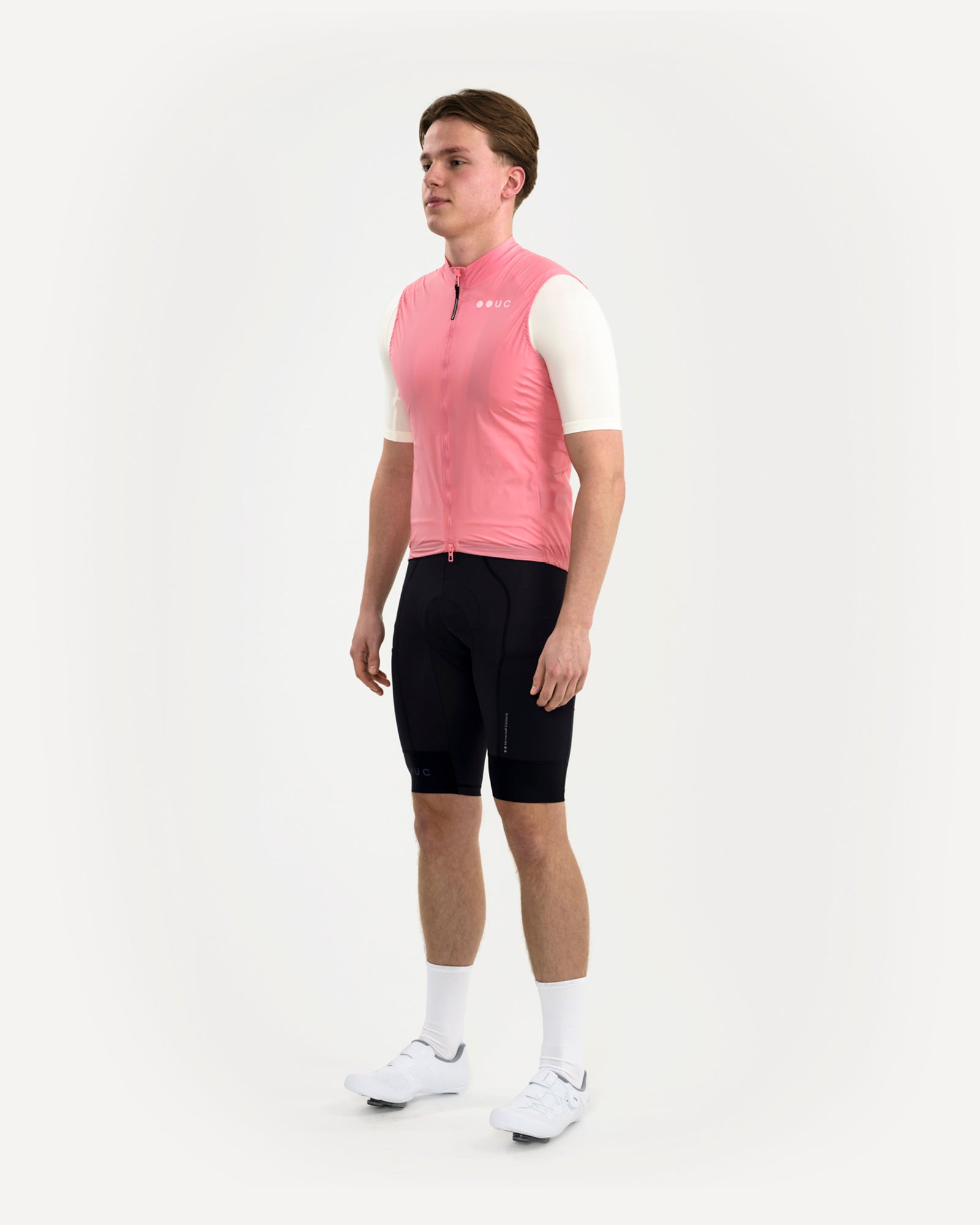 Three-quarter front view: model wearing the Men's Mono Gilet 2.0 in Washed Pink over a cream jersey and black bibs.