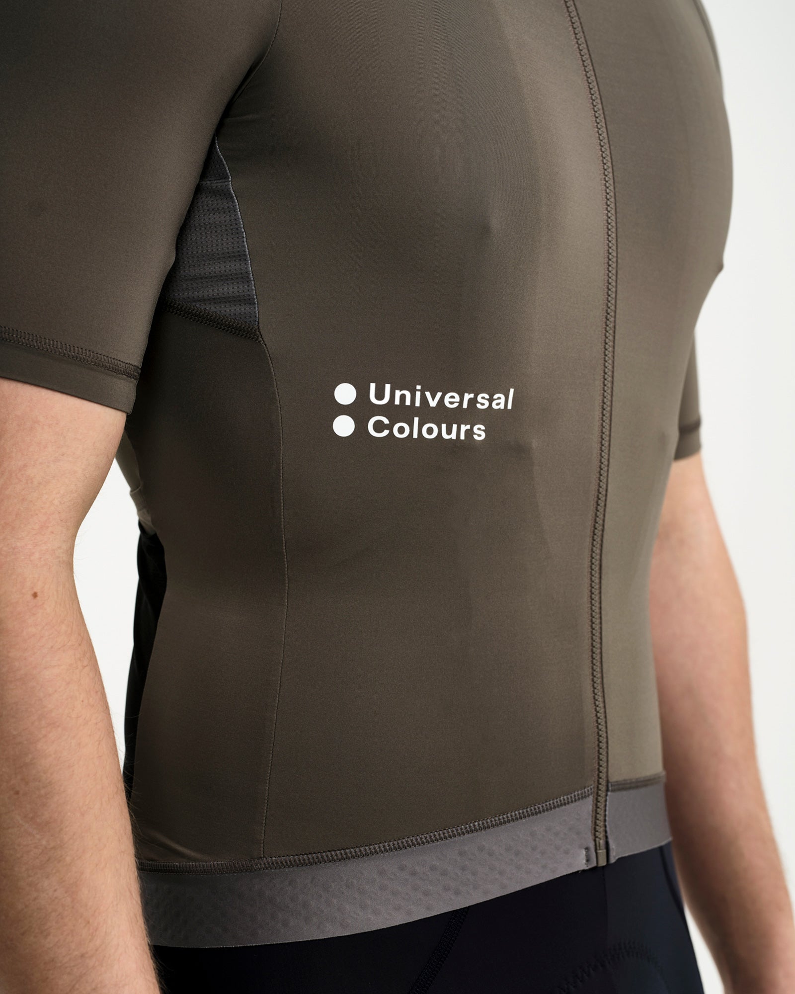 Close-up of the Universal Colours chest wordmark on the Soft Grey Men's Mono Jersey, with silicone gripper hem.