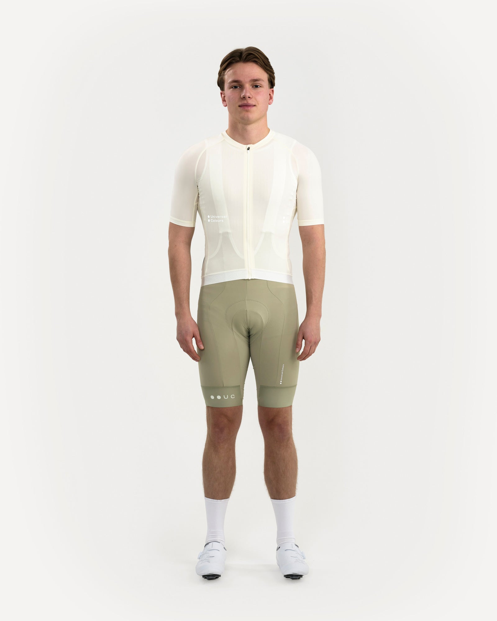Front view: model in Men's Mono Short Sleeve Jersey in Tampered White, paired with sage green bib shorts and white shoes.