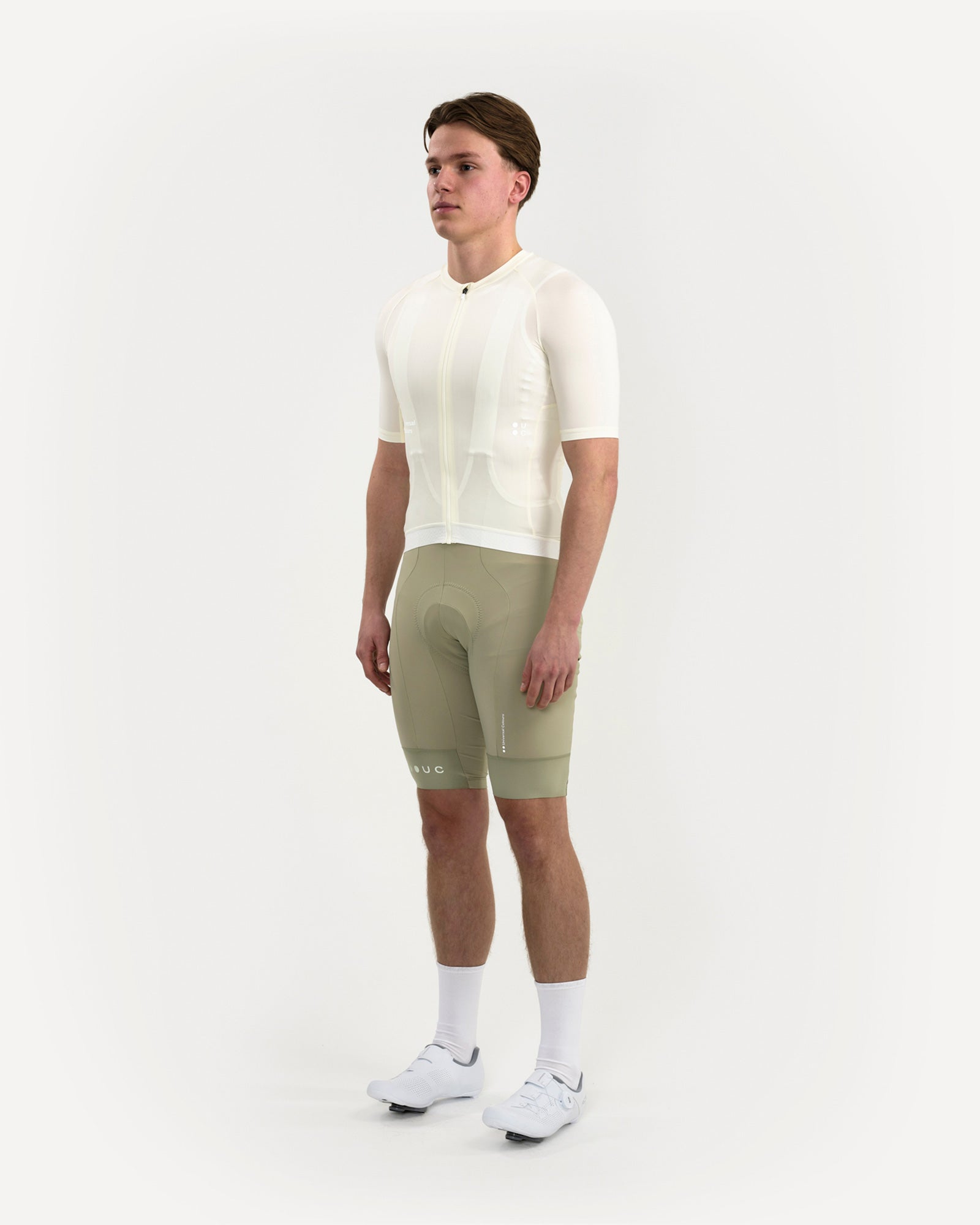 Three-quarter front view: Men's Mono Short Sleeve Jersey in Tampered White on model, paired with UC sage green bib shorts.