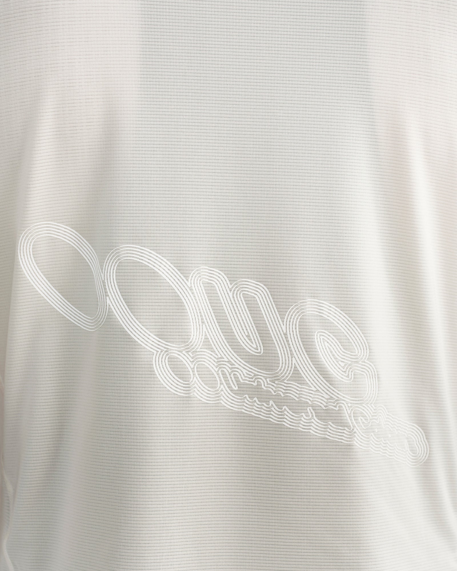 Close-up of the tonal embossed UC script logo across the lower back of the Tech Tee in Off White.