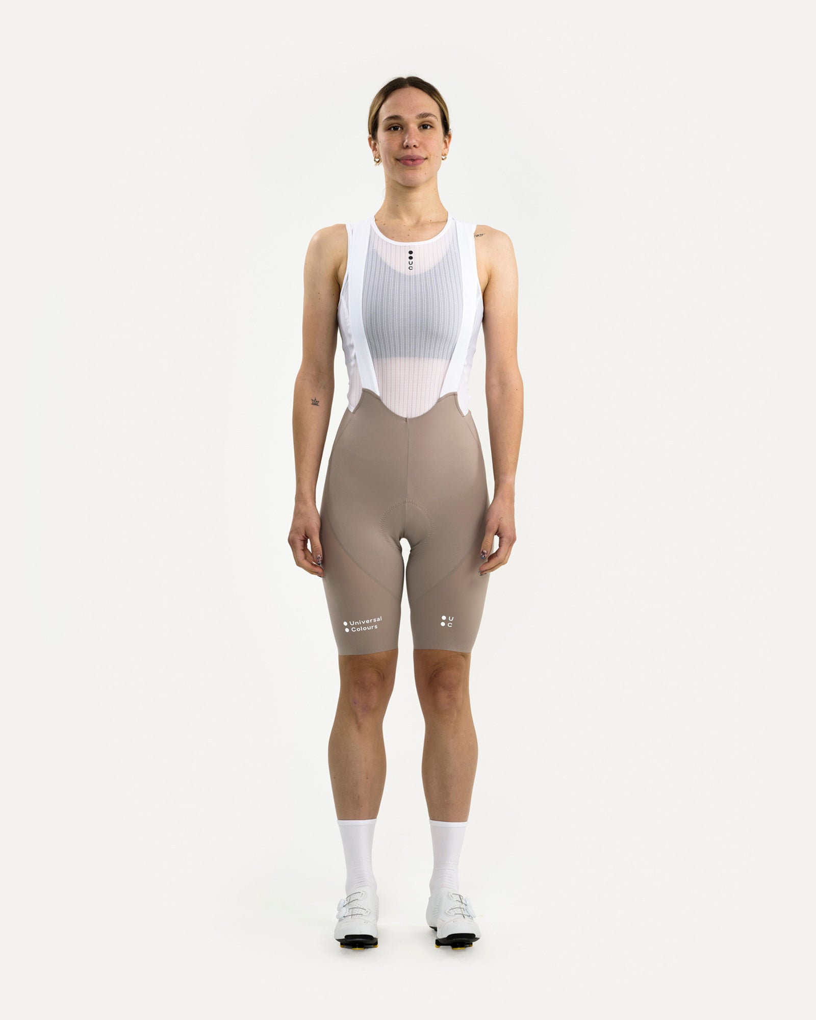 Model wearing the Women's Chroma Bib Short in Moon Grey, front view, with white mesh base layer and white cycling shoes.