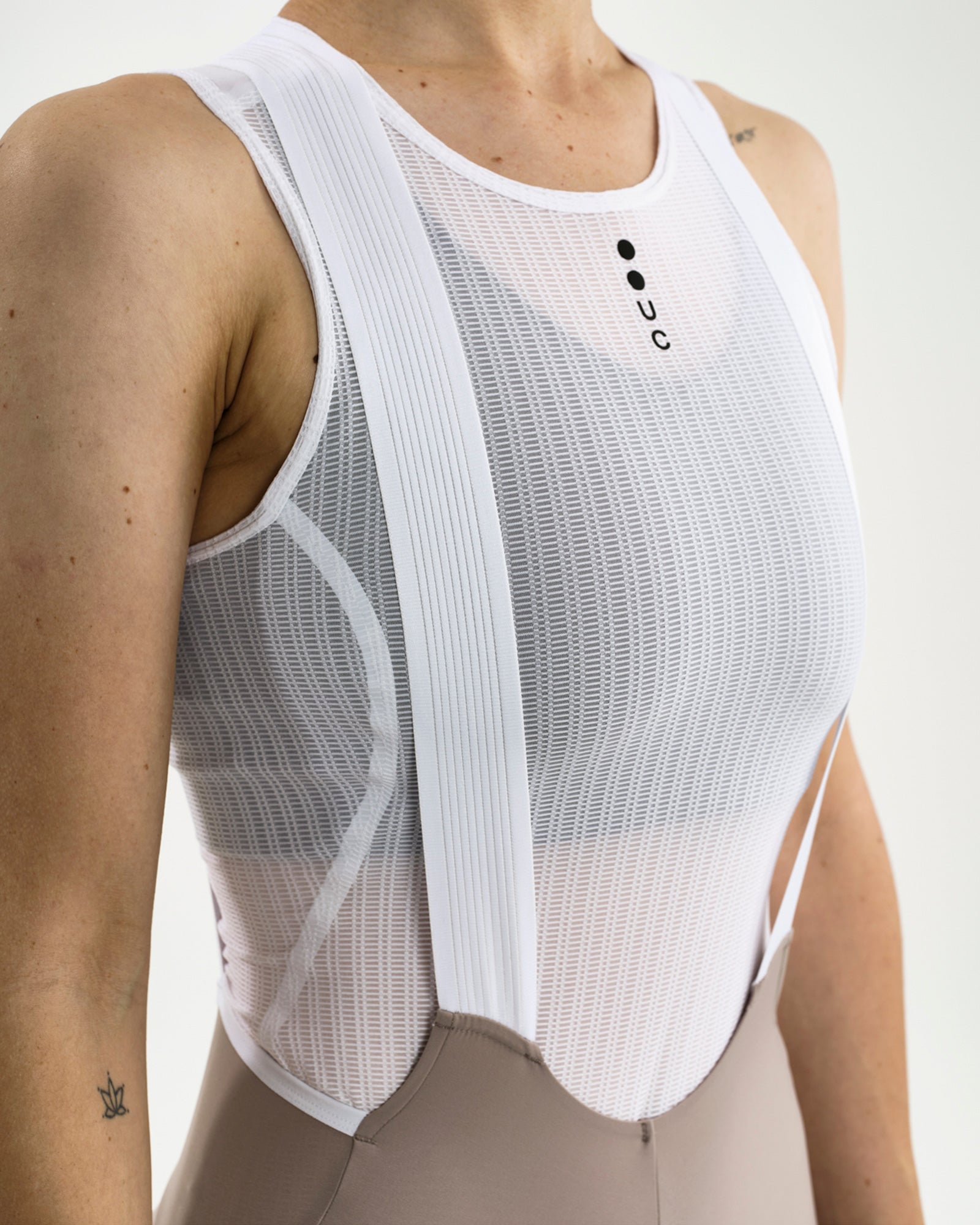 Close-up of the white mesh base layer with UC chest logo, worn under the Women's Chroma Bib Short in Moon Grey.
