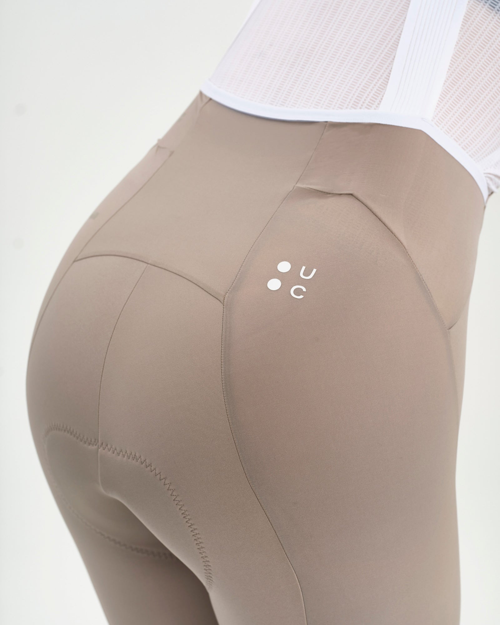 Rear hip detail: contrast white UC dot mark and curved panel seam on the Women's Chroma Bib Short in Moon Grey.
