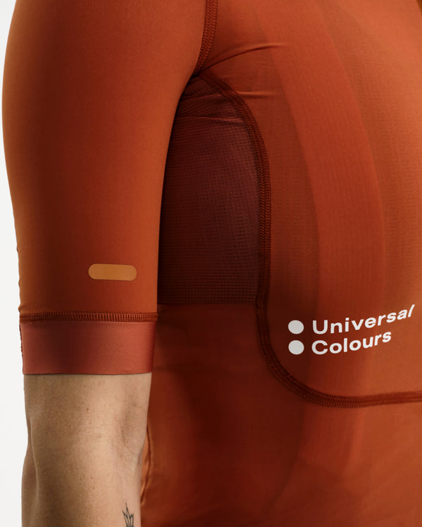 Side panel detail: mesh ventilation insert and reflective sleeve tab on the Women's Chroma Jersey in Cyprus Copper.