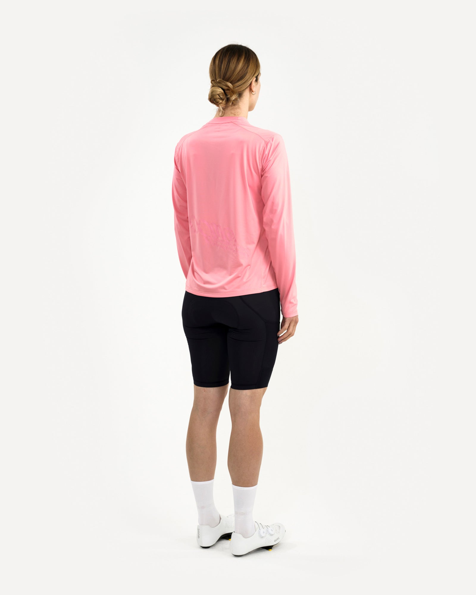 Women's back-three-quarter view of the Long Sleeve Tech Tee in Washed Pink, showing tonal back graphic and dropped hem.