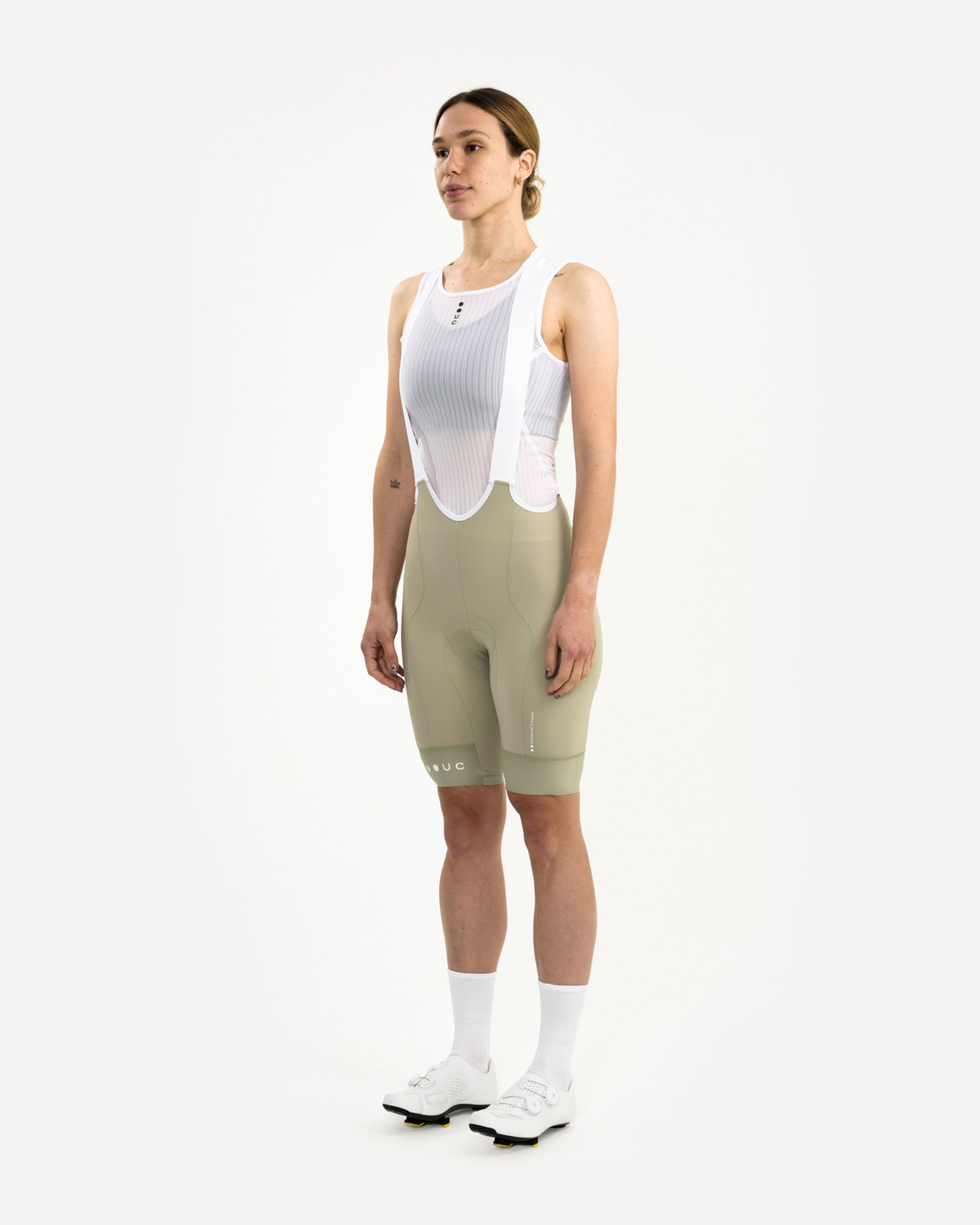 Three-quarter front view: model wearing the Women's Mono Bib Shorts 2.0 in Green Tea with a white mesh base layer.