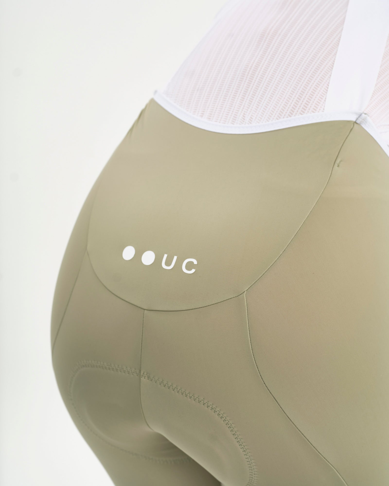 Close-up of the dropped back yoke on the Women's Mono Bib Shorts 2.0 in Green Tea, with white UC dots logo print.