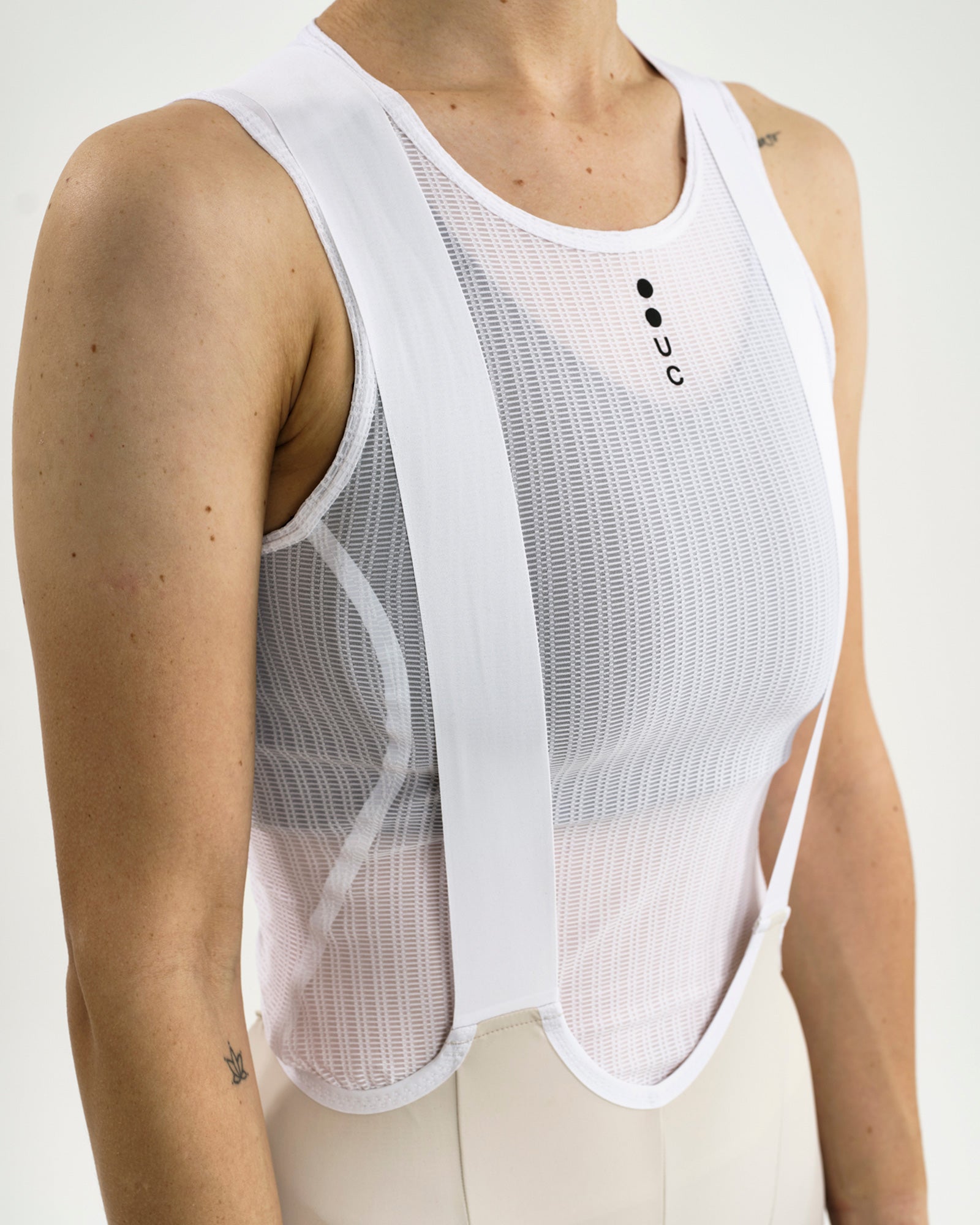 Close-up of the Women's Mono Cargo Bib Short bib upper: white mesh panel, crossover straps and black UC chest logo.
