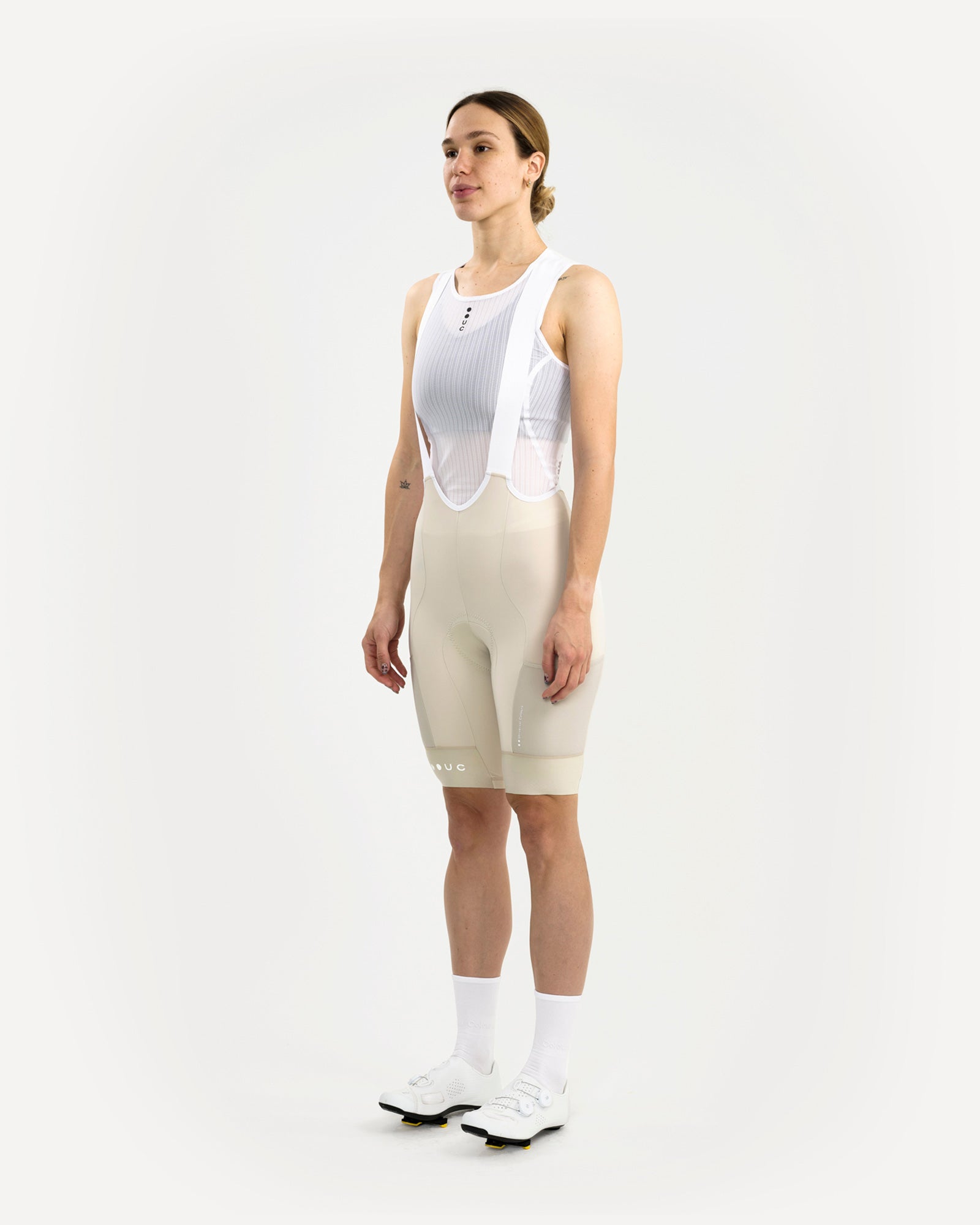 Three-quarter front view: Women's Mono Cargo Bib Short in Off White with crossover bib upper over white mesh base layer.