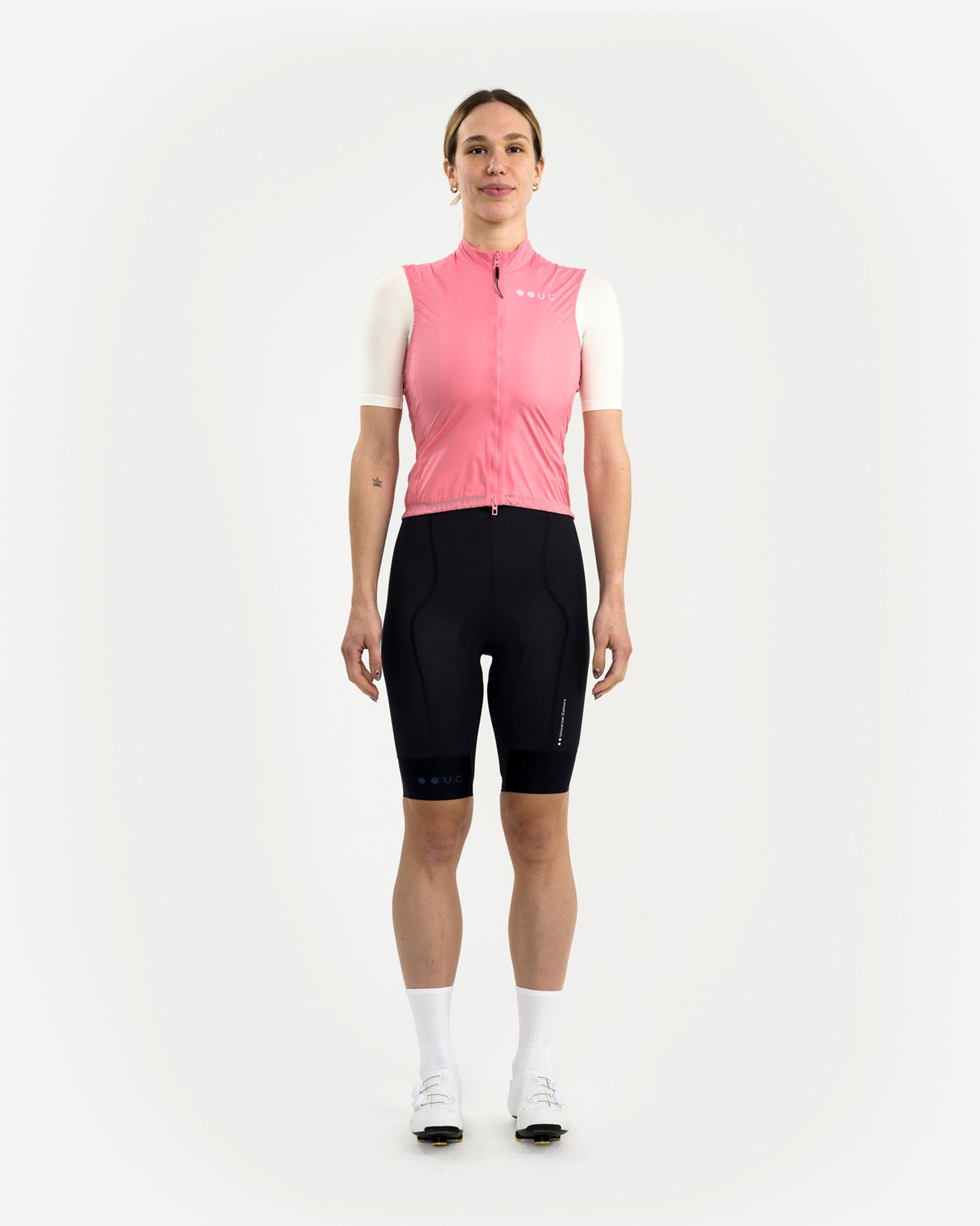 Model wearing the Women's Mono Gilet 2.0 in Washed Pink, front view, paired with a cream jersey and black UC bib shorts.