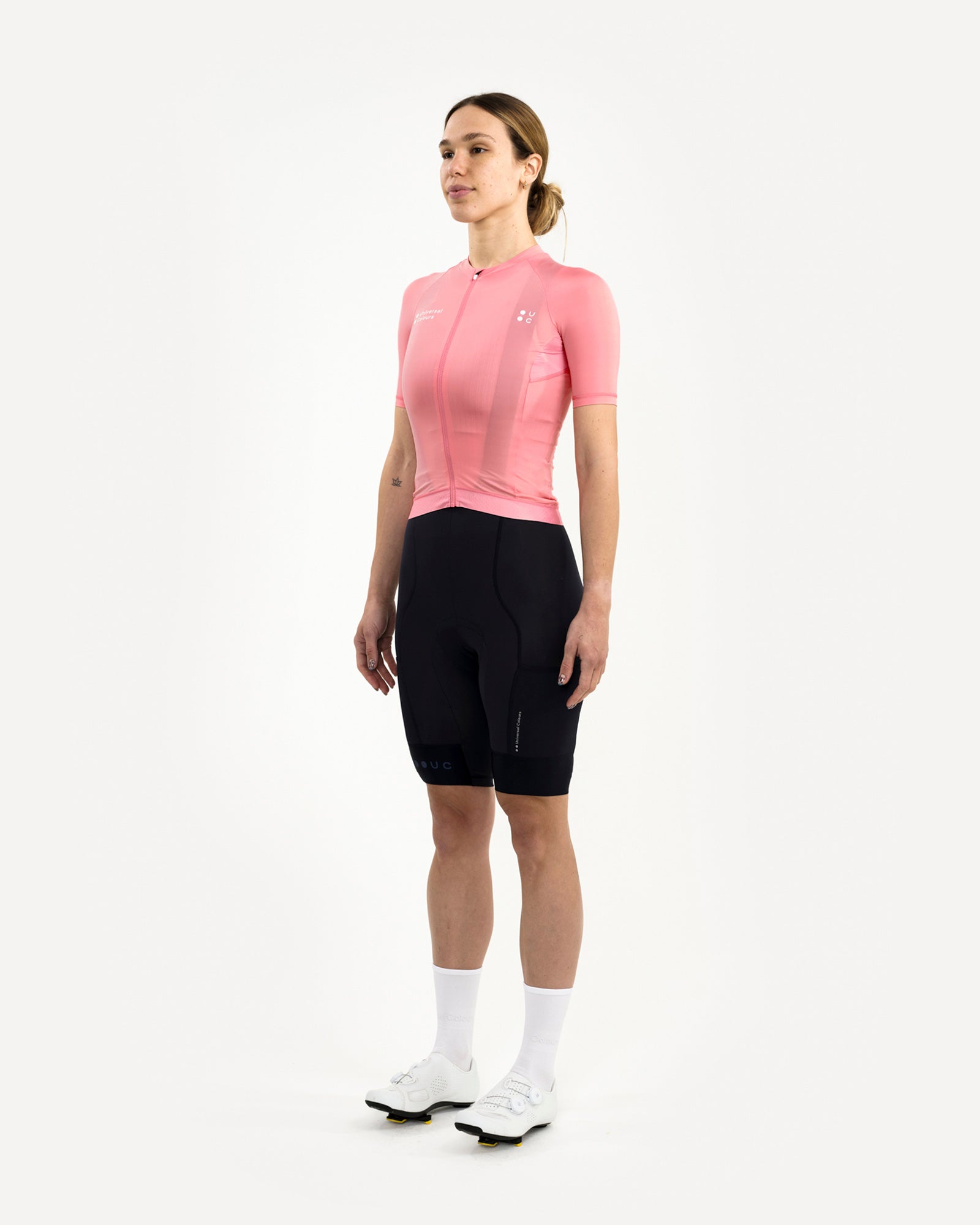 Three-quarter front view: model wearing the Women's Mono Short Sleeve Jersey in Pink with black UC bib shorts.
