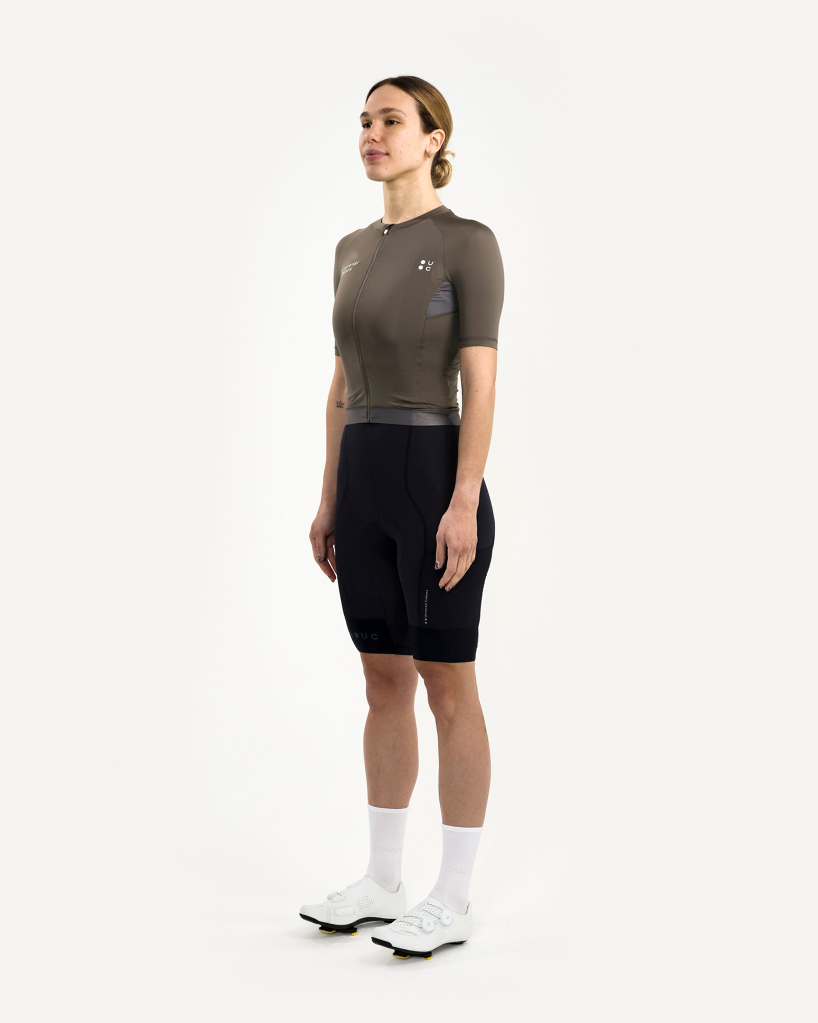 Three-quarter front: Women's Mono Short Sleeve Jersey in Soft Grey on model, with black UC bib shorts and white road shoes.