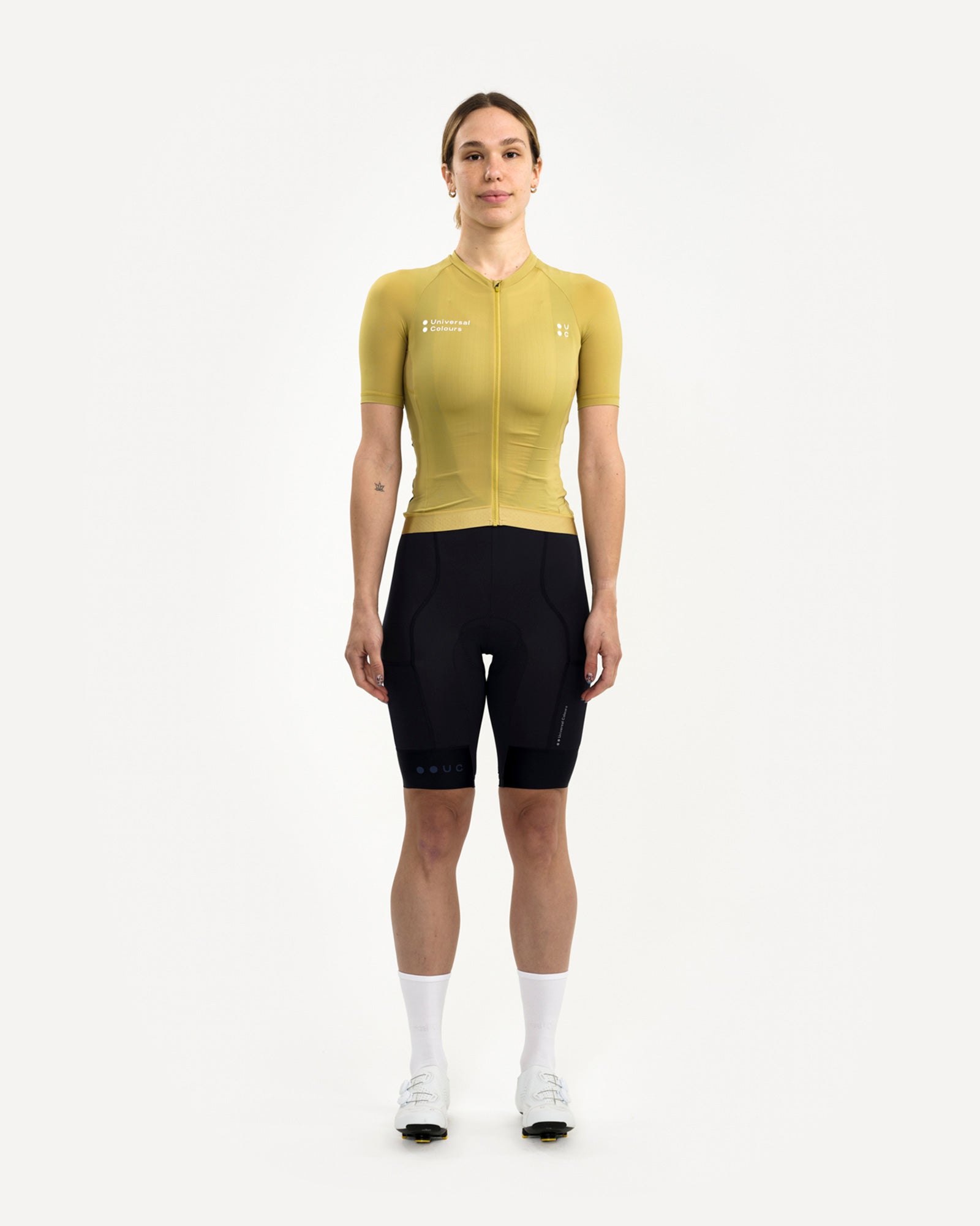 Model wearing the Acidic Yellow Mono Short Sleeve Jersey, front view, with black UC bib shorts and white cycling socks.
