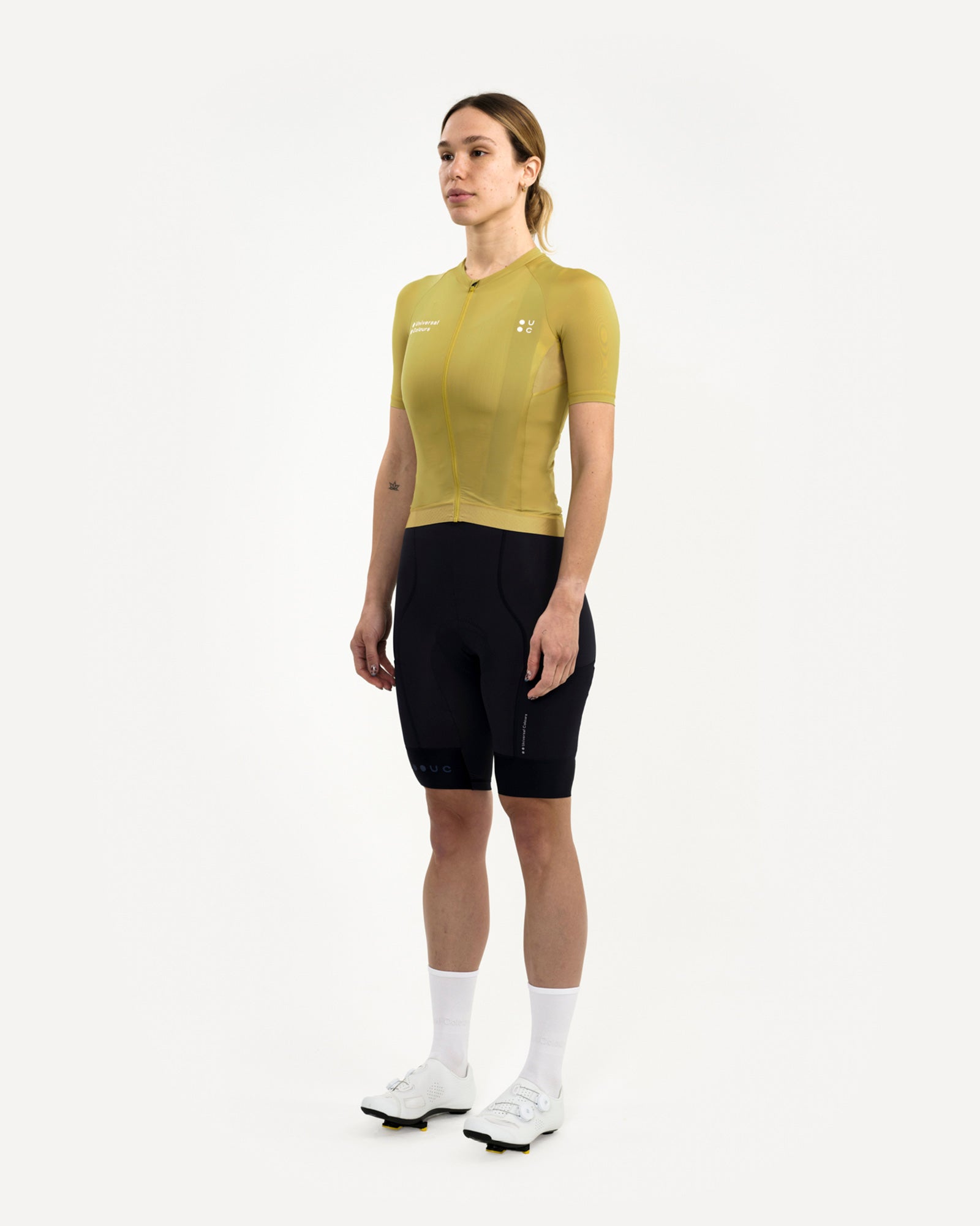Model wearing the Acidic Yellow Mono Short Sleeve Jersey, front three-quarter view, with black UC bib shorts and white socks.