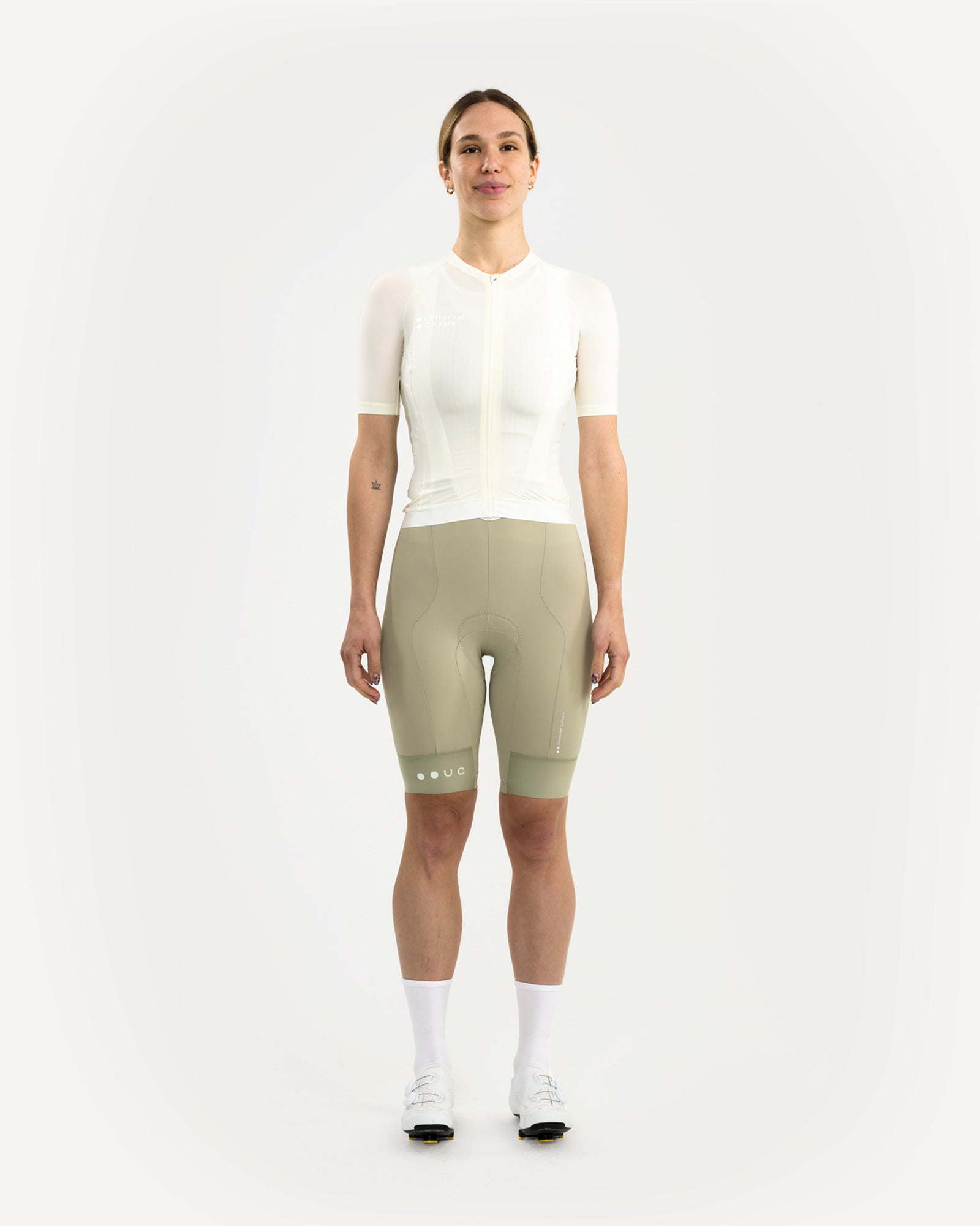 Front view: model wears the Women's Mono Short Sleeve Jersey in Tampered White with sage bib shorts and white road shoes.