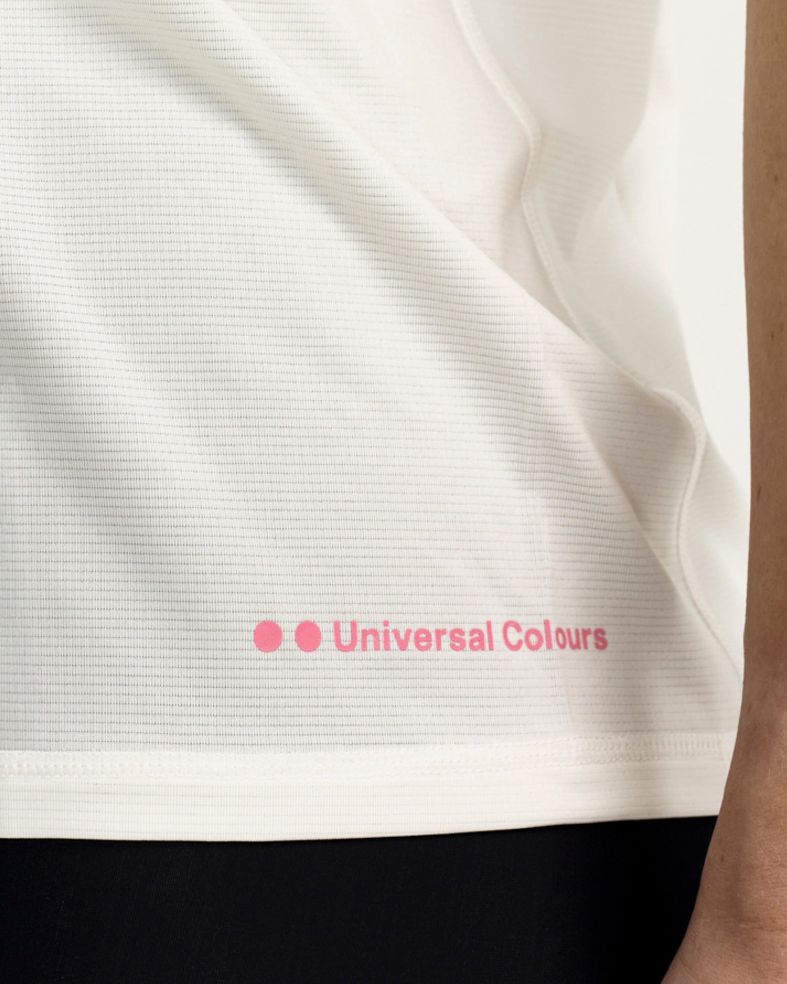 Side hem detail: pink Universal Colours wordmark print on the lower hem of the Off White Tech Tee.