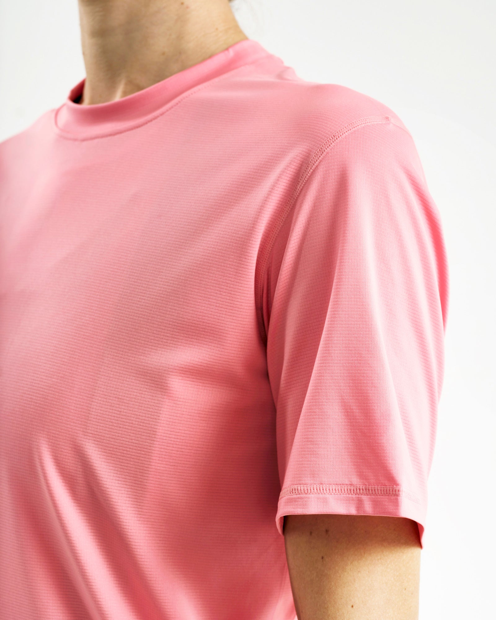 Close-up of the crew neck, raglan shoulder seam and short cap sleeve on the Tech Tee in Washed Pink.