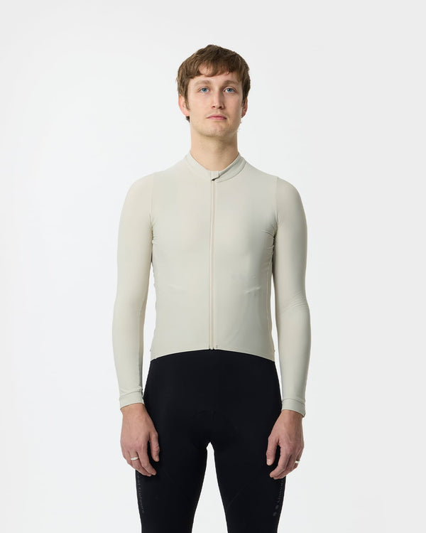 Model wearing the Men's Mono Long Sleeve Jersey in Stone White, front view, paired with black Universal Colours bib tights.