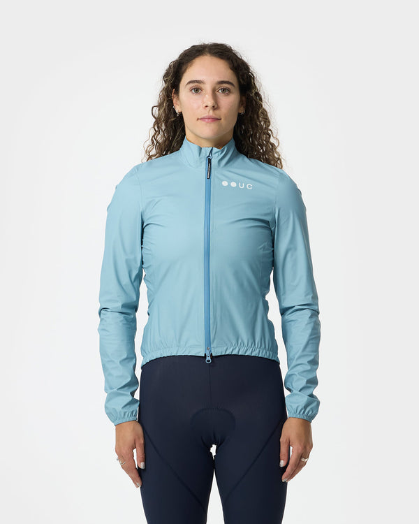 Model wearing the Women's Mono Rain Jacket in Isabel Blue, paired with navy cycling bib tights, front view.