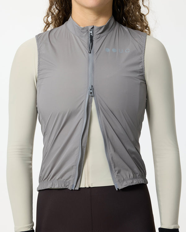 Model wearing the Women's Mono Gilet 2.0 in Shoot Grey, front zipped over a cream long-sleeve base layer and black bibs.