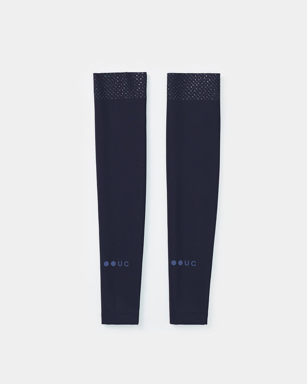 Flatlay pair of UC Arm Warmers in Navy Blue: silicone-dotted gripper cuff at the top, tonal UC roundel at the wrist.