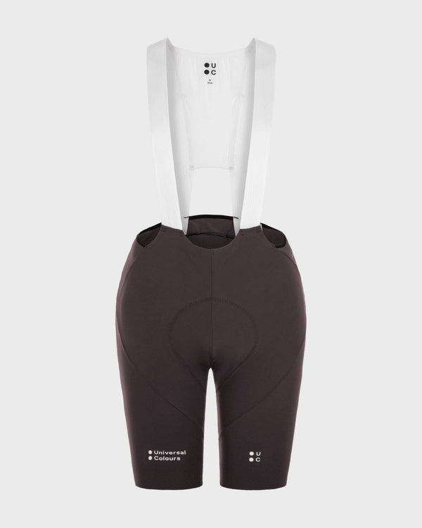 Flatlay: Men's Chroma Bib Shorts in Heavy Bark Brown with white mesh bib upper and Universal Colours hem wordmark.