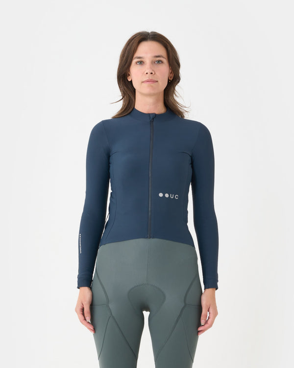 Model wearing the Women's Mono Long Sleeve Jersey in Eclipse Navy, front view, paired with sage green cycling bib shorts.