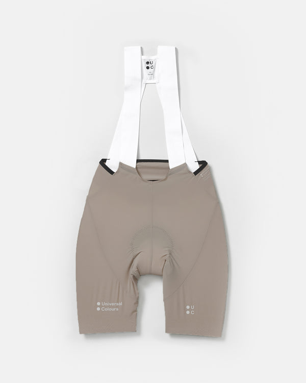 Flatlay of the Women's Chroma Bib Short in Moon Grey with white mesh shoulder straps spread above, chamois pad visible.