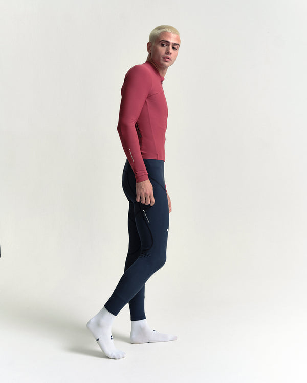 Model walking in the Men's Mono Long Sleeve Jersey in Apple Red, full-length view.